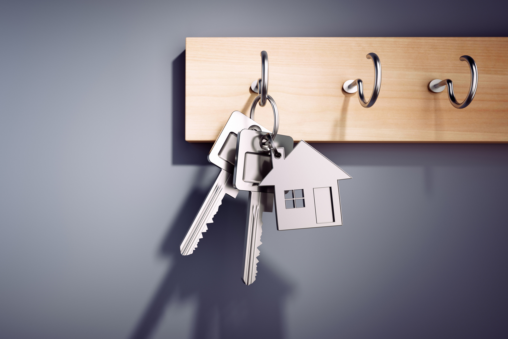 Real Estate – House Keys with Key Ring hanging on wooden Board